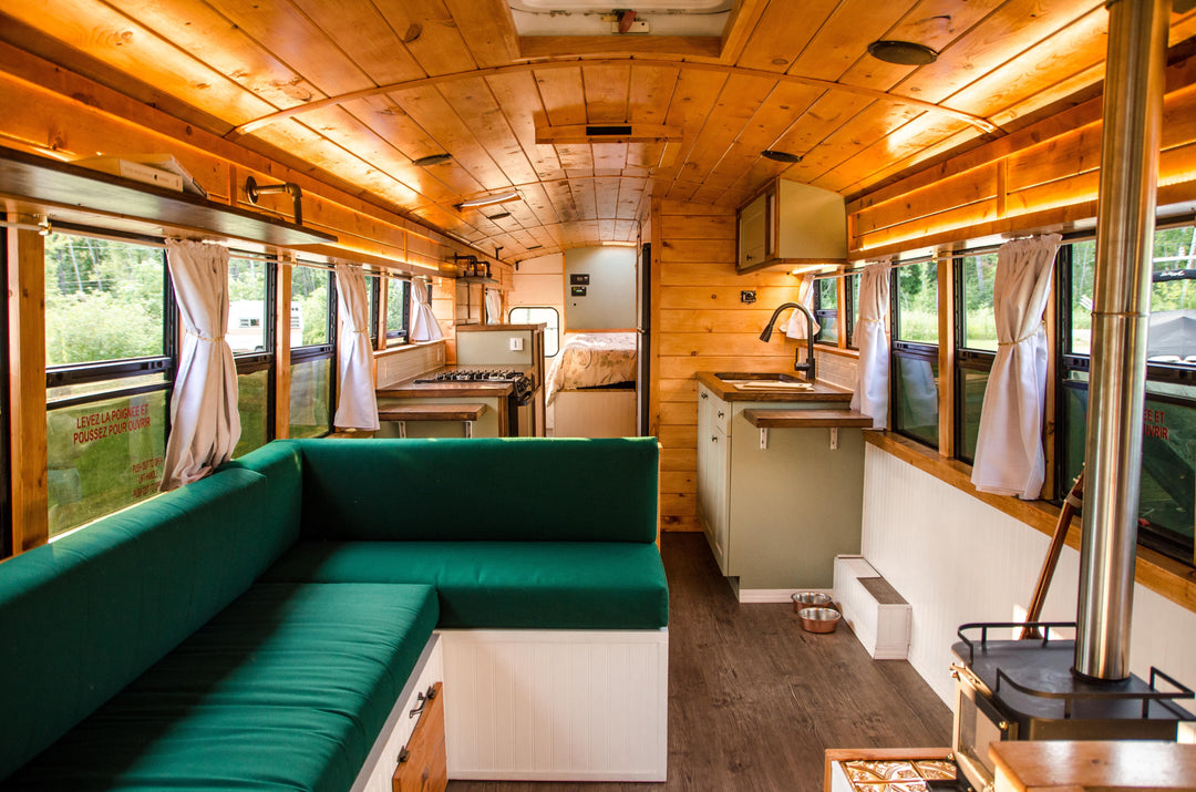cabin style school bus conversion with lots of wood and cubic mini wood burning fireplace